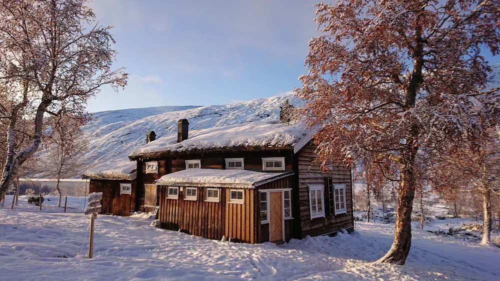 Tømmerhytte i snø.