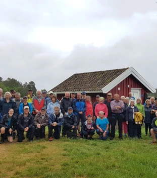 Mange mennesker står foran lite hus