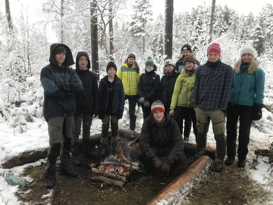 Blide ungdommer samlet rundt bålet.