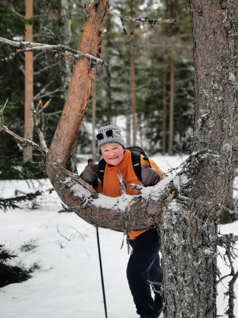 Dame lener seg mot furu og smiler