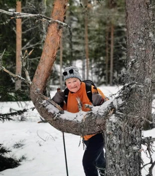 Dame lener seg mot furu og smiler
