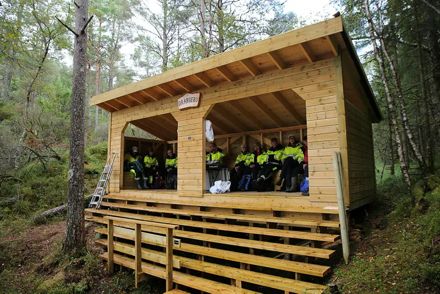 Trivselsgruppa i gule arbeidsklede inne i Drangebu gapahuk 