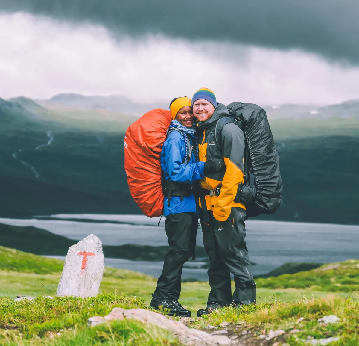 to smilende mennesker i fjellet, tåke i bakgrunnen