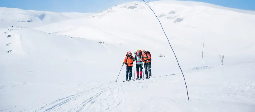 Tre personer med fjellski som går langs en kvistetløype