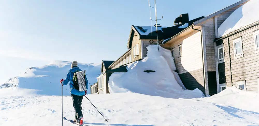 Cross country skier in front of Finsehytta on a sunny day.