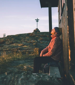 Mann lener seg mot hyttevegg