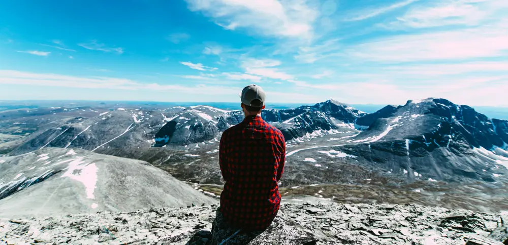 Person i rød skjorte som ser utover et fjellområde