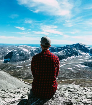 Person i rød skjorte som ser utover et fjellområde