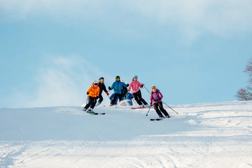 Fire skiløpere som svinger i alpinbakke.