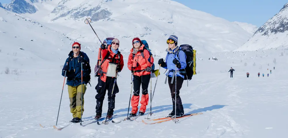 Fire personer i vinterklær med ski og staver
