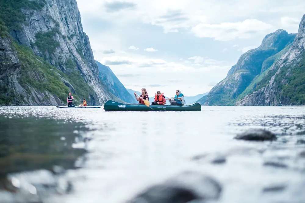 Tre personer i kano padlende i Lysefjorden.