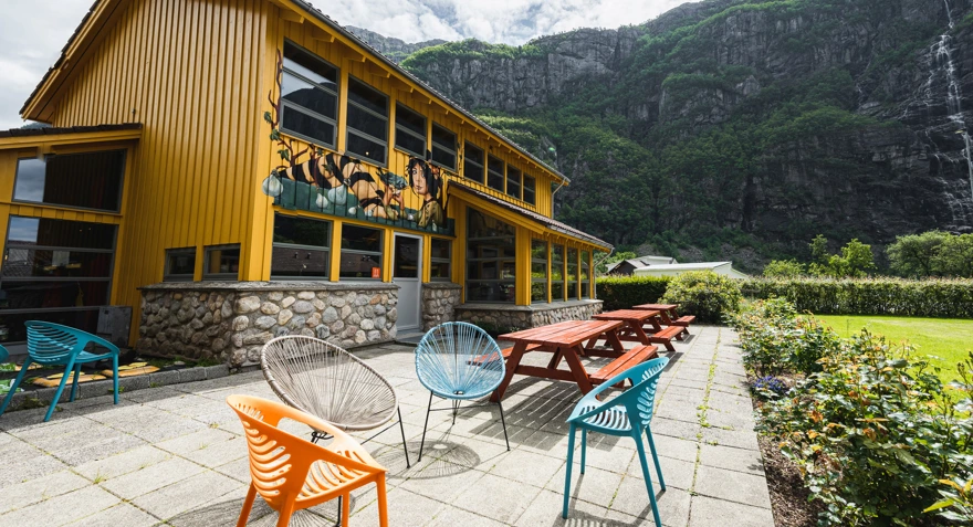 Fargerike kafestoler på en steinplatting utenfor en hytte i fargerike farger.