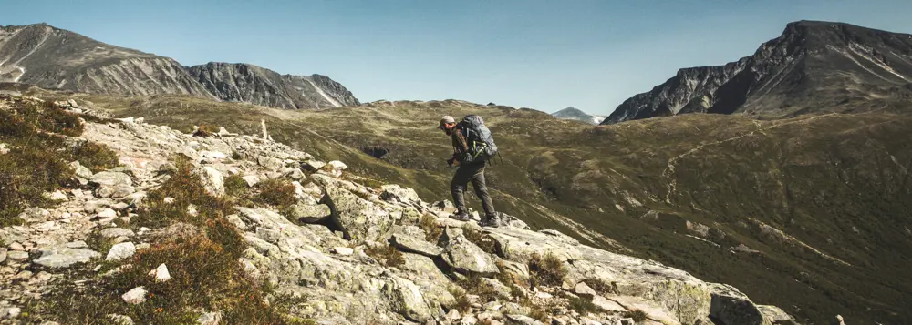 Mann med sekk som går i fjellet