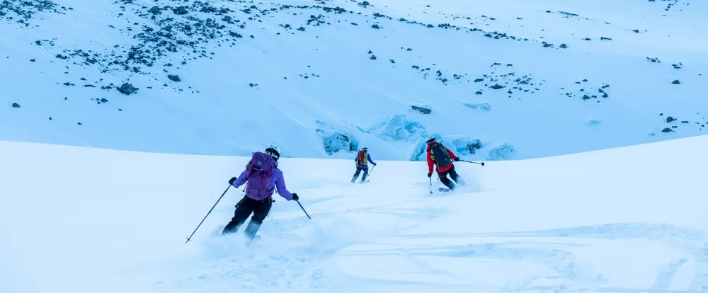 Tre personer kjører nedover på ski