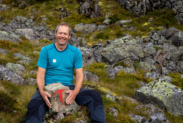 En mann sitter med en stein mellom beina som er merket med en rød T.