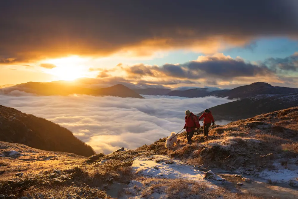 To personer på tur over skydekkede fjell.