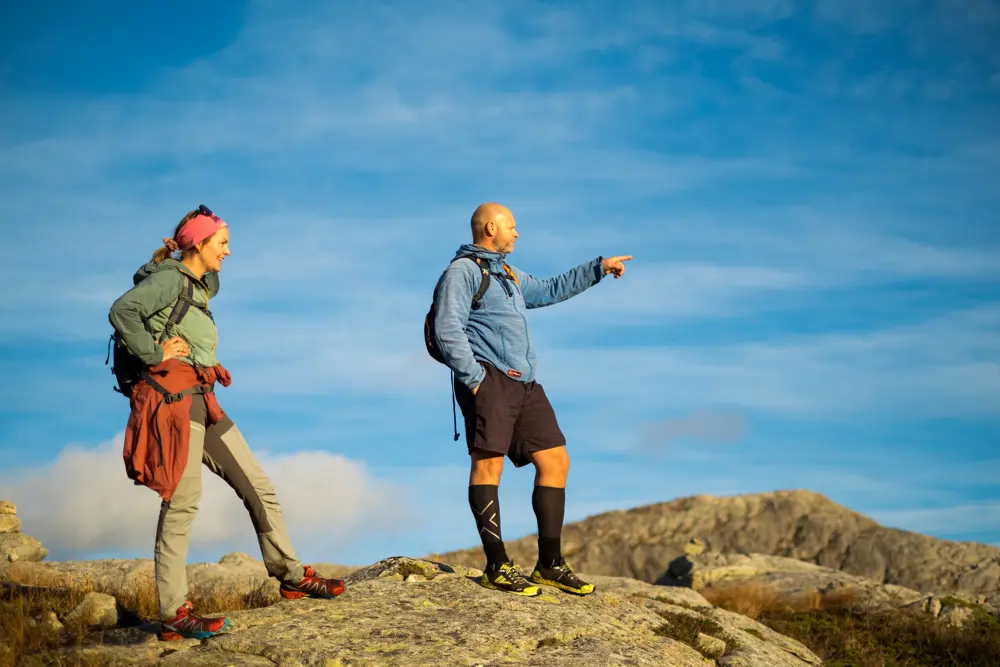 To personer står på et fjel og speider utover. Han ene peker