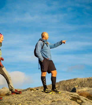 To personer står på et fjel og speider utover. Han ene peker