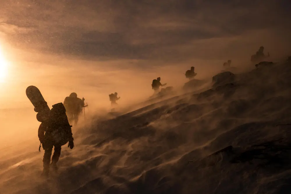 Mennesker går opp på fjell i snøen