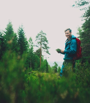 Mann med kompass i skogen