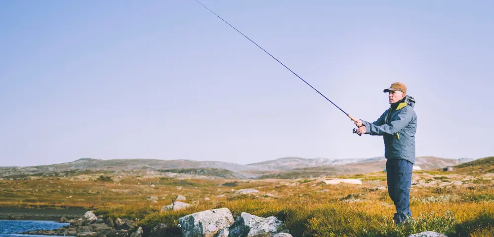 Mann med fiskestang i fjellandskap
