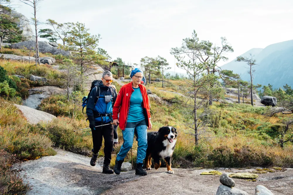 En mann går tur sammen med en dame som har gåstav og hund
