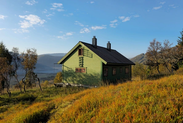 Grønn hytte i dal med høstfarger.