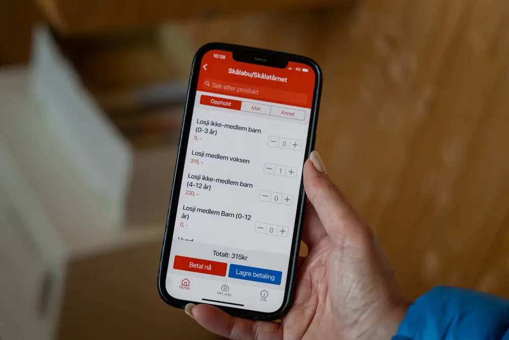 Mobiltelefon i hånden med ulike hyttekategorier.