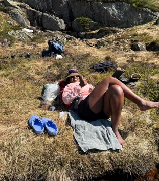 En dame ligger i gresset og soler seg.