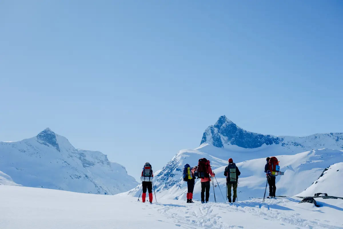 En gruppe mennesker som ser utover et snødekket fjellandskap
