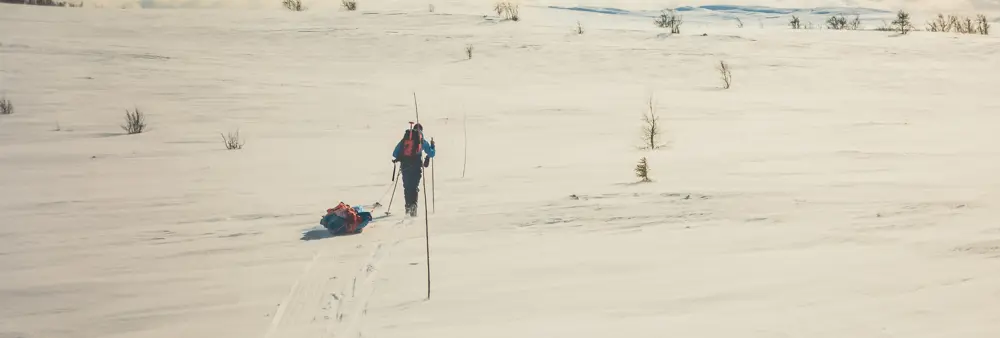 En person som går på ski med pulk i vinterfjellet