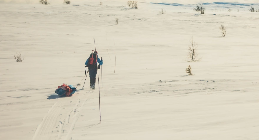En person som går på ski med pulk i vinterfjellet