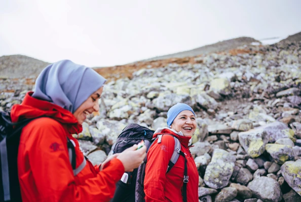 To kvinner med turlederjakker i fjellet
