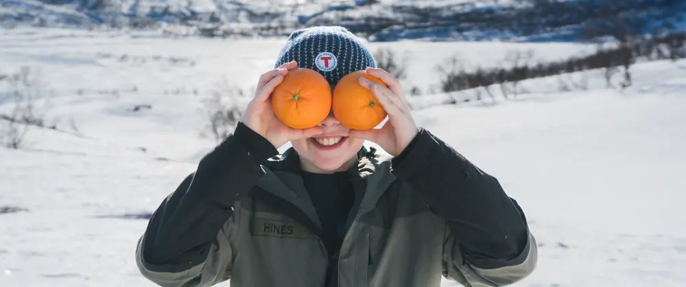 Gutt som holder to appelsiner foran ansiktet
