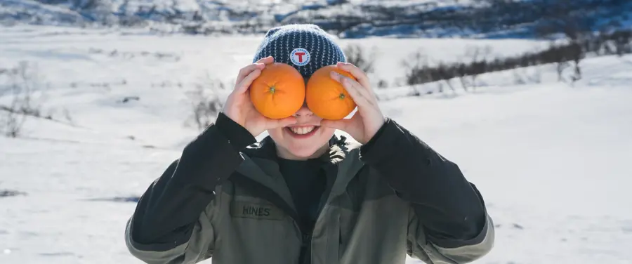 Gutt som holder to appelsiner foran ansiktet