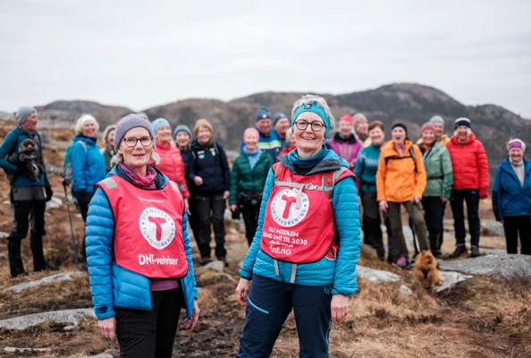 Bilde av to damer i rød T-vest foran et turfølge.