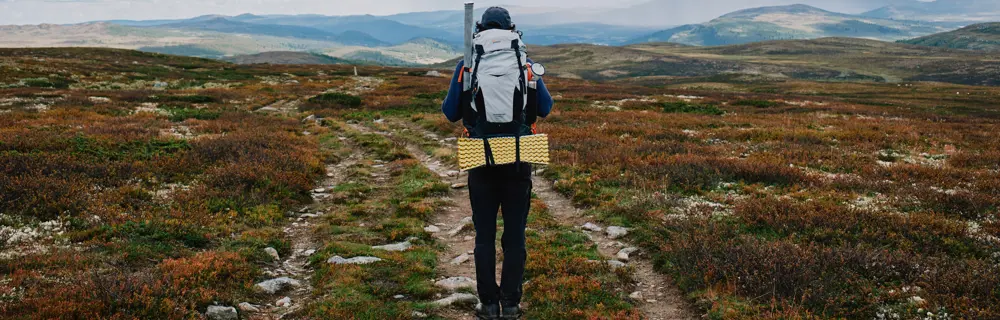 En mann med sekk som går tur i fjellet