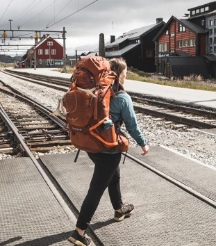 Person med ryggsekk som går over toglinjer.