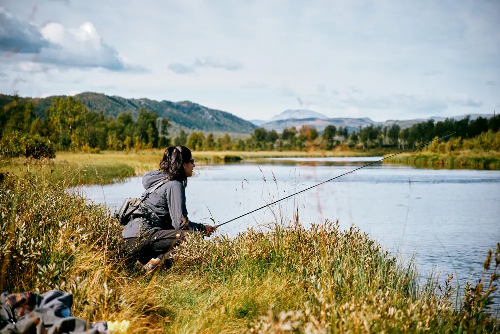 Kvinne med fiskestang i fjellandskap