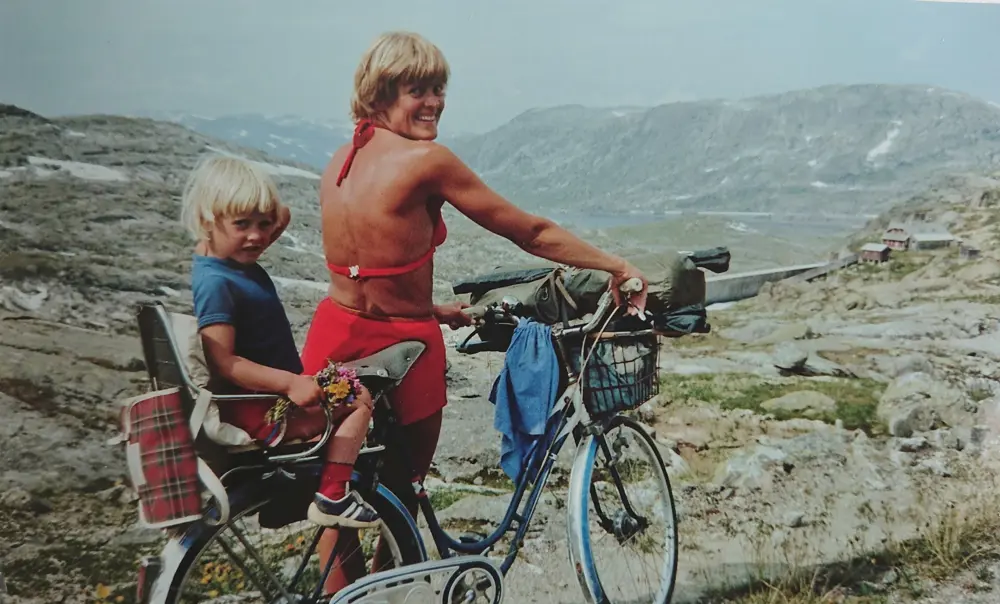 Finalebilder fra våren 2018. DNTs fotokonkurranse. Tema: Historiske bilder.
Mor og dotter på sykkeltur på Rallarvegen retning Hallingskeid sommaren 1981. Det var annan trend då med tregirs sykkel og ingen hjelm på verken vaksene eller born. Innsendar av biletet er meg, Heidi Reisegg Endal, som sit bak på sykkelen. Det er min far Richard Jacobsen som har teke biletet. Sykkelen fekk mor mi (Tove Reisegg Jacobsen) i konfirmasjonsgåve i 1962. På den tida var det eksklusivt å ha sykkel med tre gir.
Mine foreldre har samtykka til at eg kan sende inn biletet.