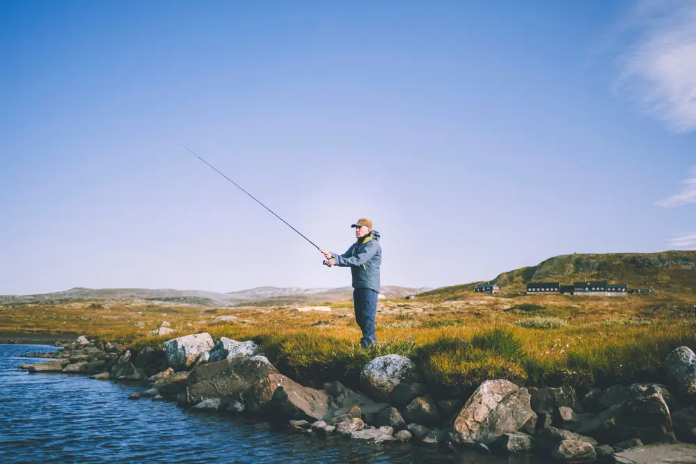 Reportasjetur over Hardangervidda i forbindele med jubileumsbok. Turgåer fisker ved vannet nedenfor Litlos turisthytte.