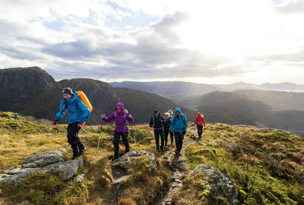 En gruppe seniorer går på sti oppover et fjell