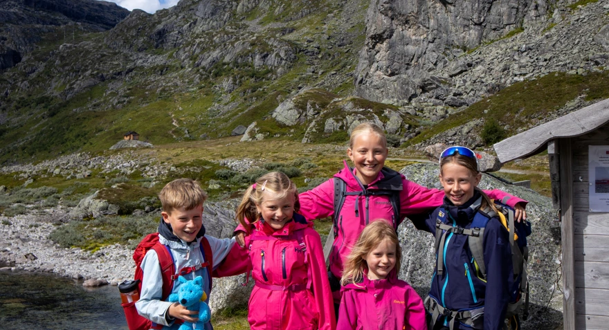 En gjeng med barn holde rundt hverandre og smiler i kamera.