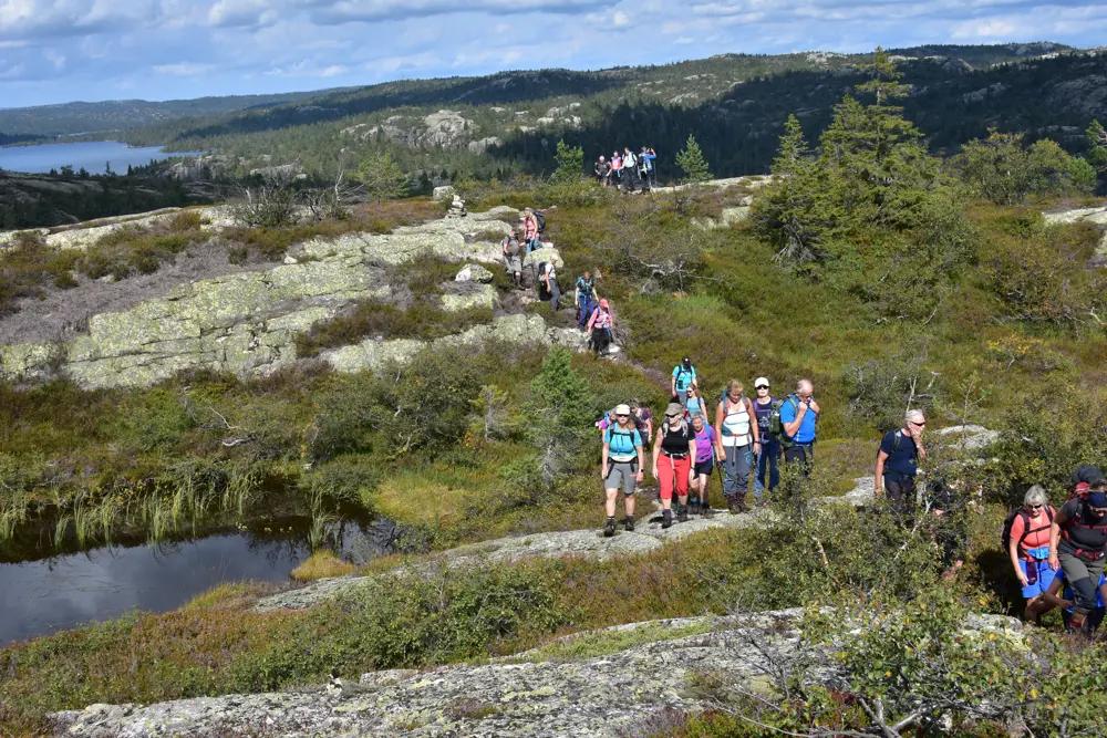 Innsjø og fjell på sommeren med en gruppe mennesker på tur