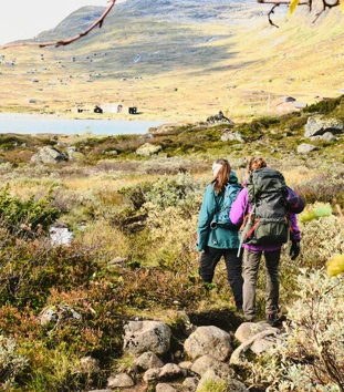 To personer med sekk som går på en sti i grønt fjellterreng