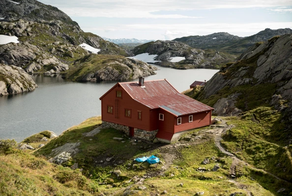 Slitt, rød hytte i fjellet.