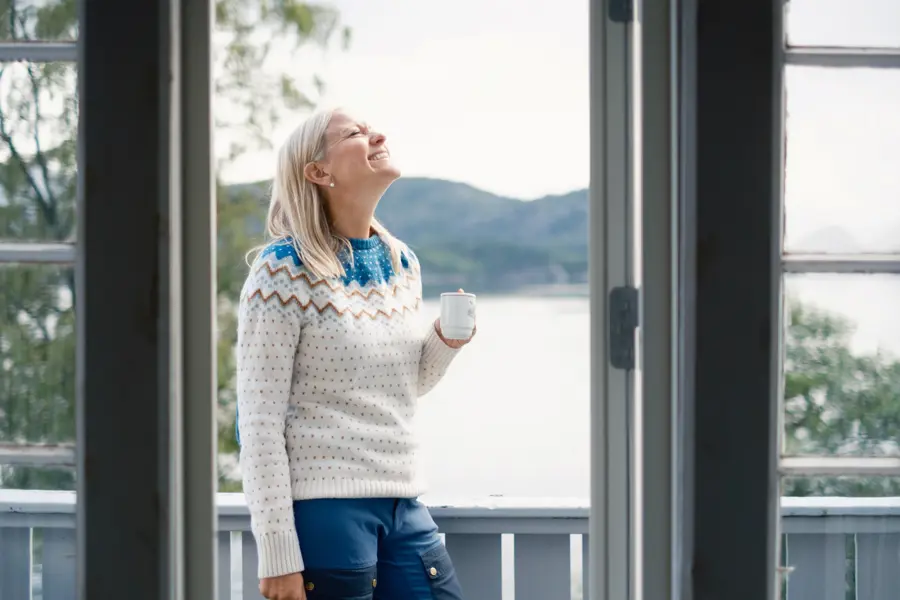 Agnethe Larsen drikker kaffe på terrassen på Nodhagen turisthytte, Sandnes. Kyst, kysthytte.